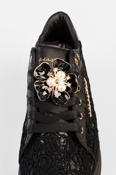 black lace sneaker with a gold and pearl flower ornament on the laces