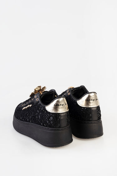black lace sneakers with gold metallic heel patches and a thick black platform sole