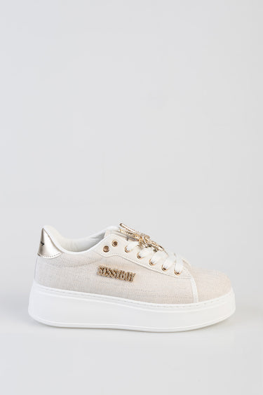 beige canvas sneakers with a white chunky sole, gold eyelets and a gold lace charm