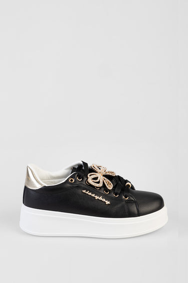 black leather sneakers with white chunky sole, gold eyelets, and decorative gold bow laces; silver heel tab