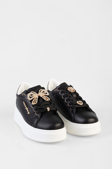 two black sneakers with white sole and rhinestone bow accents on the laces