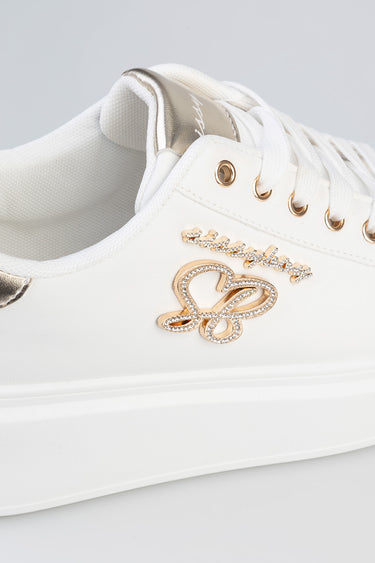 white sneaker with gold metallic tongue, crystal heart emblem and white laces