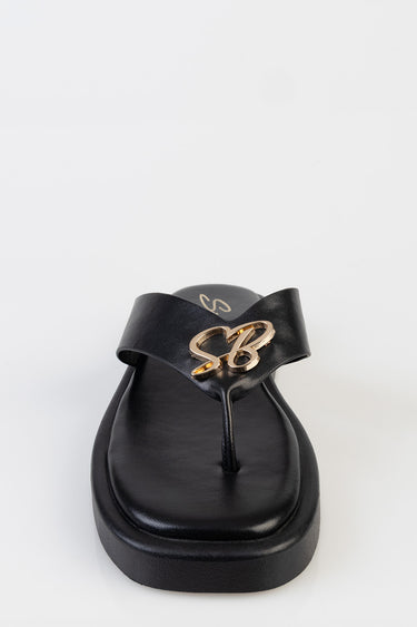 black leather thong sandal with a wide strap and a gold initials emblem on the front