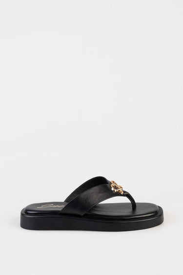 black leather thong sandal with a gold emblem on the strap and a chunky sole