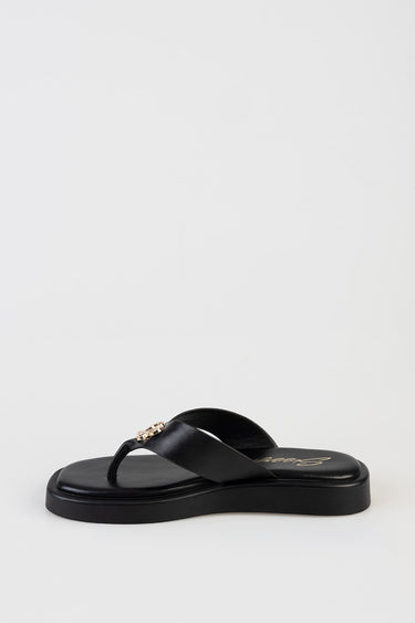 black thong sandal with a gold decorative emblem on the strap and a cushioned sole