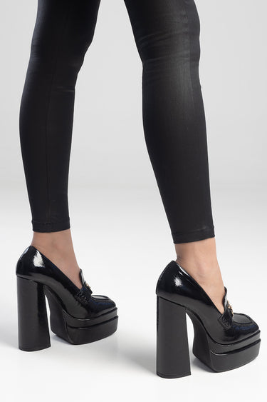 black patent platform heels with thick block heels worn by a model in black leggings