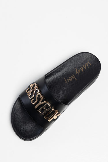 black flat slide sandal with a wide strap and gold metal logo lettering