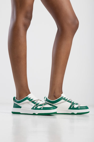 green and white sneakers with white laces on a model's legs side view