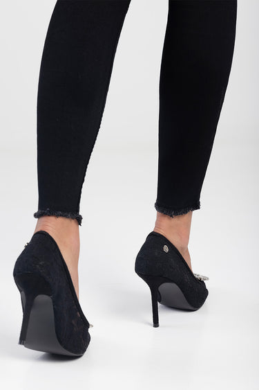 woman wearing black lace stilettos with frayed ankle jeans, back view of the heels