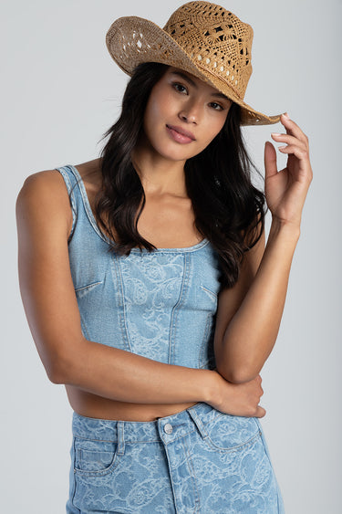 woman wearing a woven straw cowboy hat and light blue denim top with lace pattern