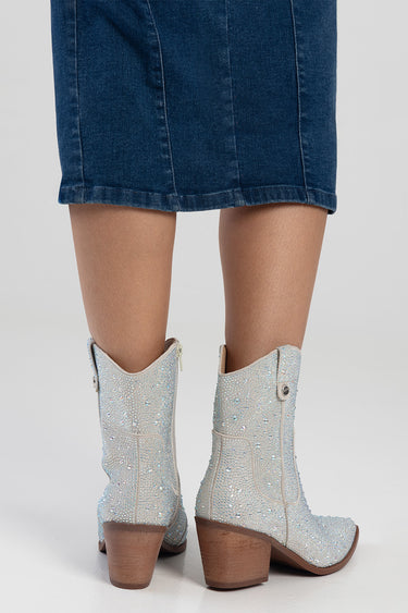 glittery light blue western style boots with brown stacked heel beside a denim skirt