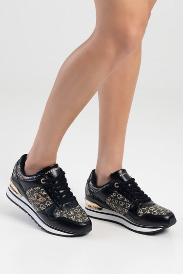 black sneakers with gold logo pattern and white sole on a model's legs