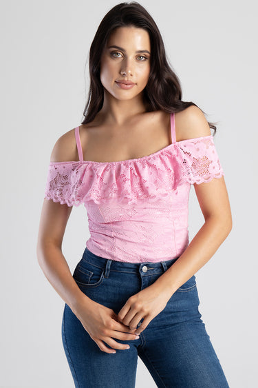 woman wearing pink lace off-shoulder top with ruffle and spaghetti straps, paired with dark blue jeans