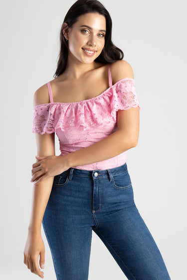woman wearing a pink lace off-shoulder top with ruffle sleeves and blue jeans