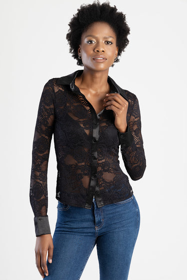 woman wearing a sheer black lace blouse with a satin collar and cuffs, button front, from Blue Jean Traders, paired with