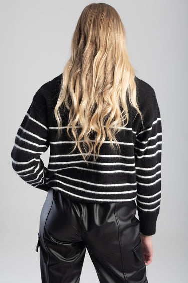 back view of a person wearing a black and white striped knit sweater and black leather pants