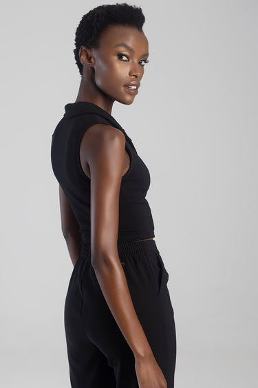 woman model wearing a black sleeveless waistcoat with collar and black pants side view