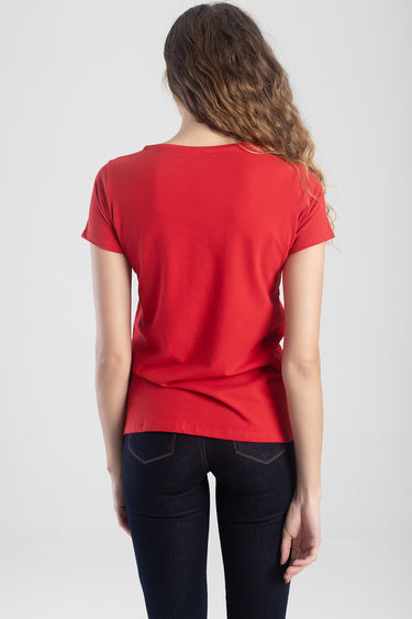 back view of a red short sleeve top worn with dark blue jeans against a light background