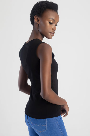 side view of a woman wearing a black sleeveless top and blue jeans