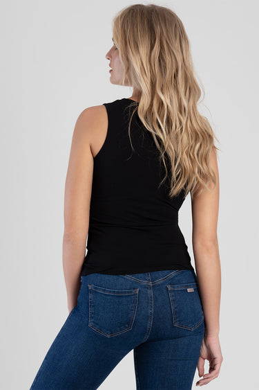 back view of a woman wearing a black sleeveless top and blue denim jeans