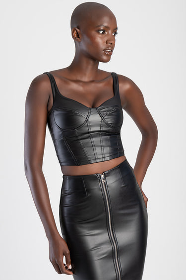 woman in black faux leather corset top with structured cups and wide straps, paired with a high waisted black leather skirt