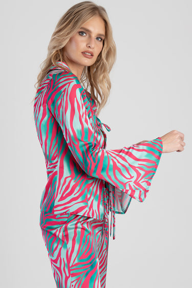 woman in a pink and teal zebra print blouse with wide bell sleeves and a waist tie