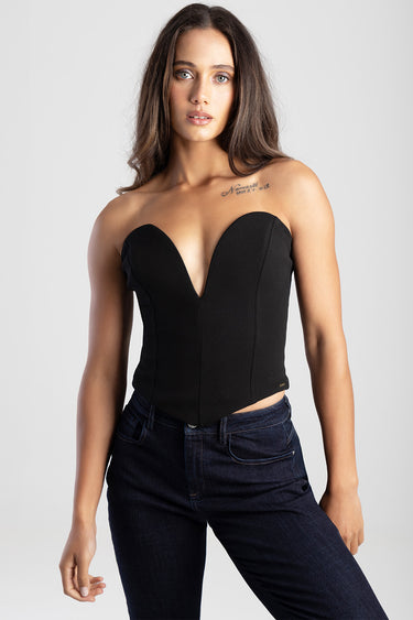 woman in a black strapless corset top with a plunging sweetheart neckline, paired with dark denim jeans; tattoo on her