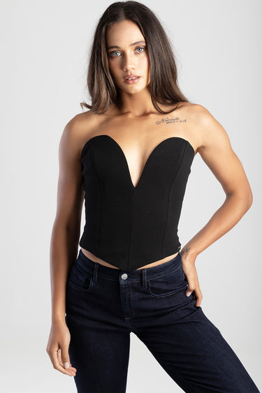 woman in a black strapless corset top with a deep sweetheart neckline and dark jeans