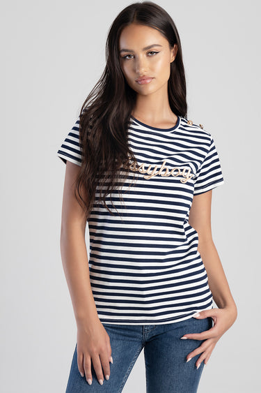 model wearing navy and white striped short sleeve top with gold cursive logo across chest and shoulder button detail