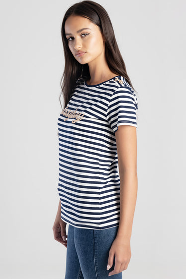 woman wearing navy and white striped short sleeve top with gold script logo on the chest and gold button accents at the