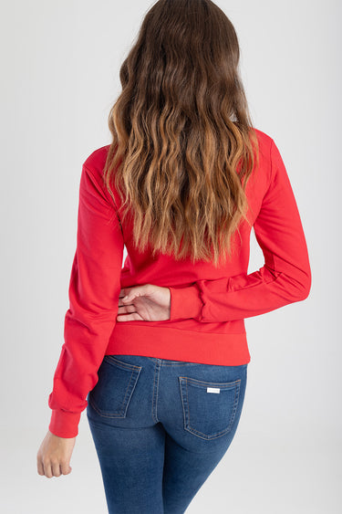 back view of a woman in a red long sleeve top and blue denim jeans