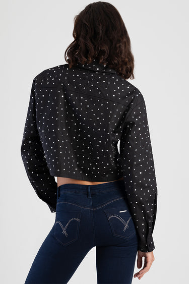 back view of cropped black shirt with white polka dots and long sleeves, paired with dark blue jeans