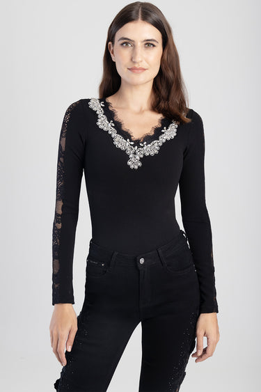 woman in black long sleeve bodysuit with cream lace embroidery at the V neckline and lace sleeves, paired with black jeans