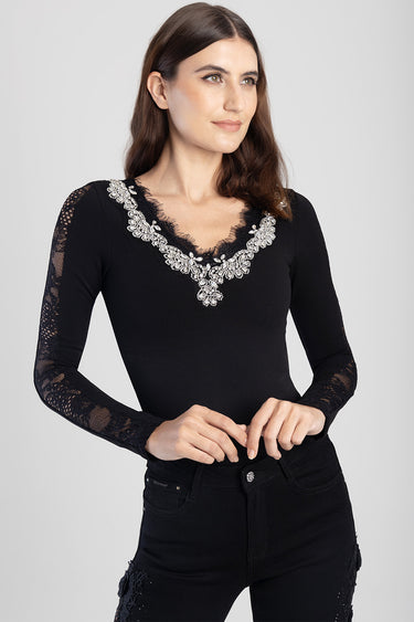 woman wearing a black long sleeve bodysuit with lace sleeves and sparkling silver embroidery along the neckline