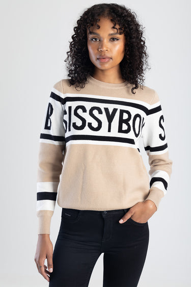 woman wearing beige knit top with white and black stripes and bold lettering across the chest, long sleeves