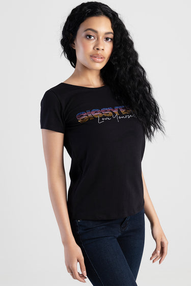 woman in black short sleeve top by Blue Jean Traders with a glitter rainbow logo across the chest