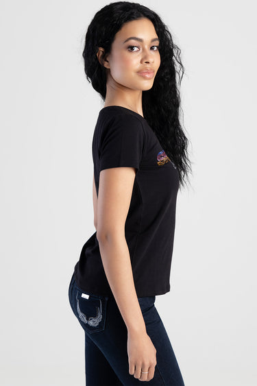 woman in a black short sleeve top with a small colorful graphic and dark blue jeans with an embroidered back pocket