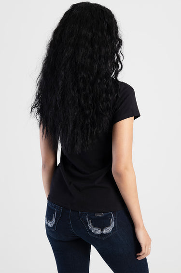 woman back view wearing black short sleeve top and dark blue jeans with silver wing embroidery on back pockets