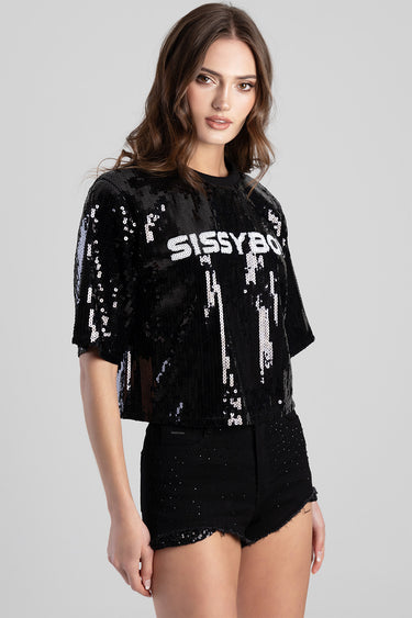 model wearing a black sequin top with short sleeves and a round neck featuring bold white lettering across the chest paired