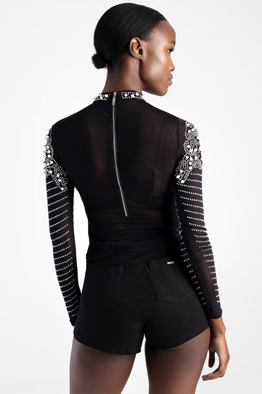 woman seen from behind wearing a black sheer long sleeve bodice with pearl embellishments on sleeves and collar, silver