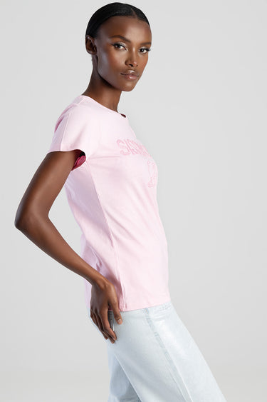 woman wearing pastel pink short sleeve t shirt with logo graphic, paired with light blue jeans, side profile