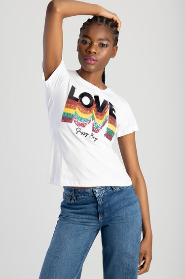 woman wearing white short sleeve top with rainbow sequin love graphic and blue jeans