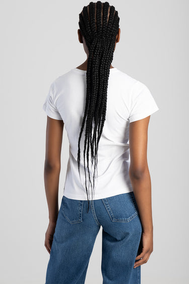 woman seen from behind wearing a white short sleeve top and blue jeans; long braids fall down her back