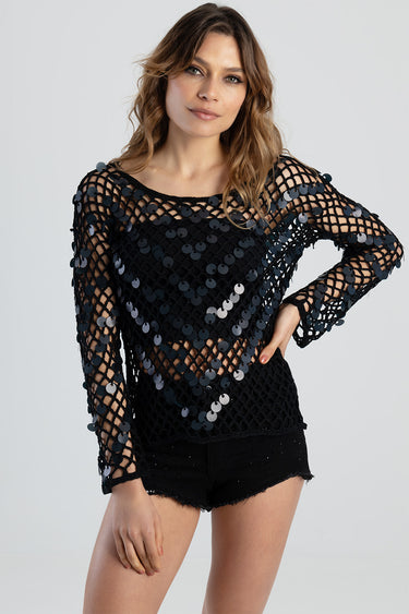 woman wearing black knitted mesh top with large sequins and black shorts