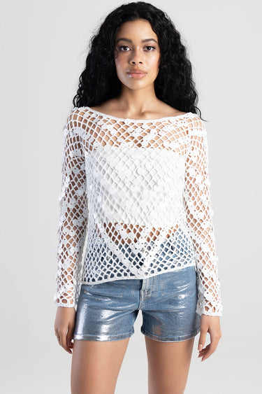 model wearing white crochet knit top with circular appliques and long sleeves, paired with silver metallic shorts