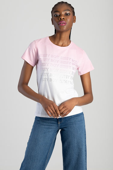 woman wearing a pink to white gradient short sleeve top with repeated text across the chest, paired with blue jeans