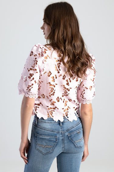 pink floral lace top with short sleeves and scalloped hem worn with light blue jeans, shown from the back