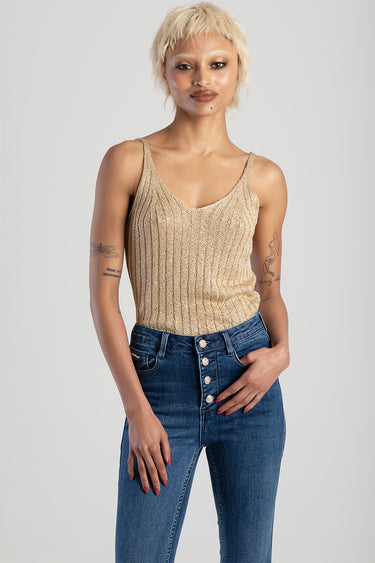 model wearing a shimmering gold knit vest with thin straps paired with high rise blue denim jeans