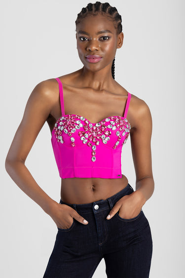 woman in a hot pink cropped corset top adorned with rhinestones and thin straps, paired with dark jeans