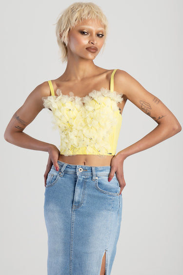 yellow sleeveless corset top with floral tulle embellishments worn with light denim skirt